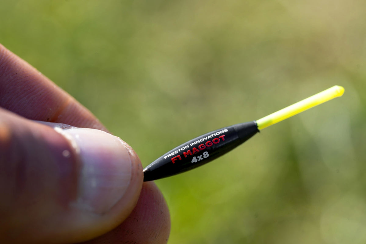 Preston F1 Maggot 4x8 dobber met gele antenne tussen de vingers