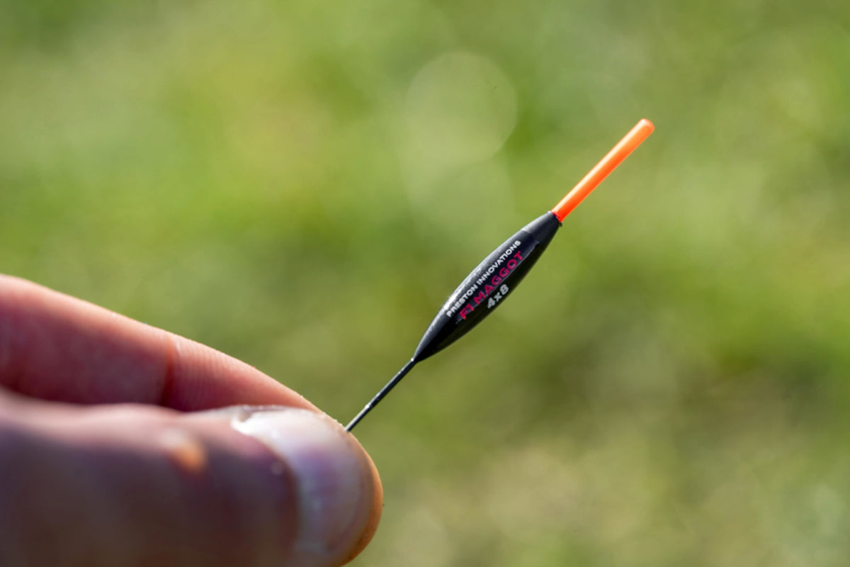 Preston F1 Maggot 4x8 dobber met rode antenne tussen de vingers