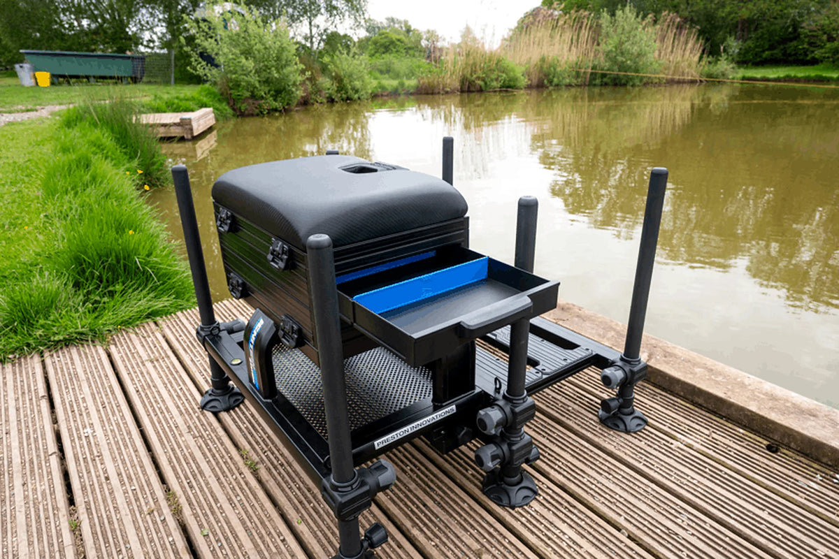 Preston Ignition Station SL Seatbox – geopende frontlade met blauwe verdeling op een houten vissteiger