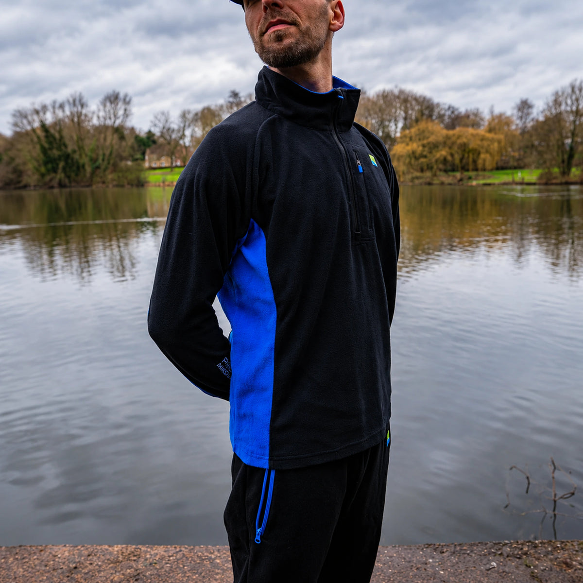 Preston Micro Fleece, gedragen zijaanzicht aan de vijver met blauw zijpaneel en borstzak