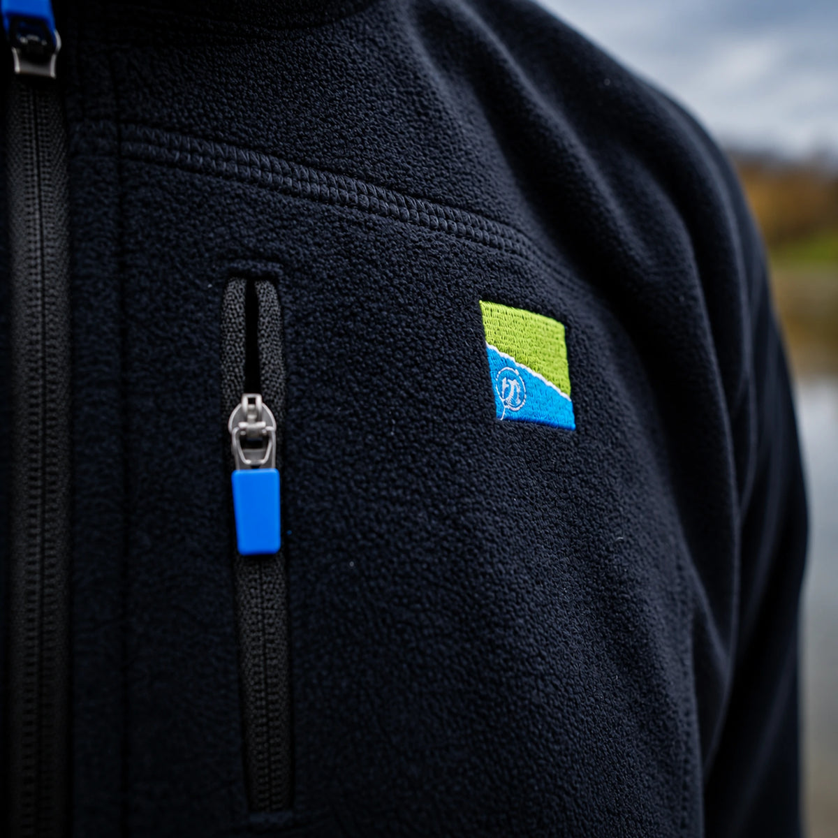 Preston Micro Fleece, detail van de borstzak met blauwe ritstrekker en geborduurd Preston-logo