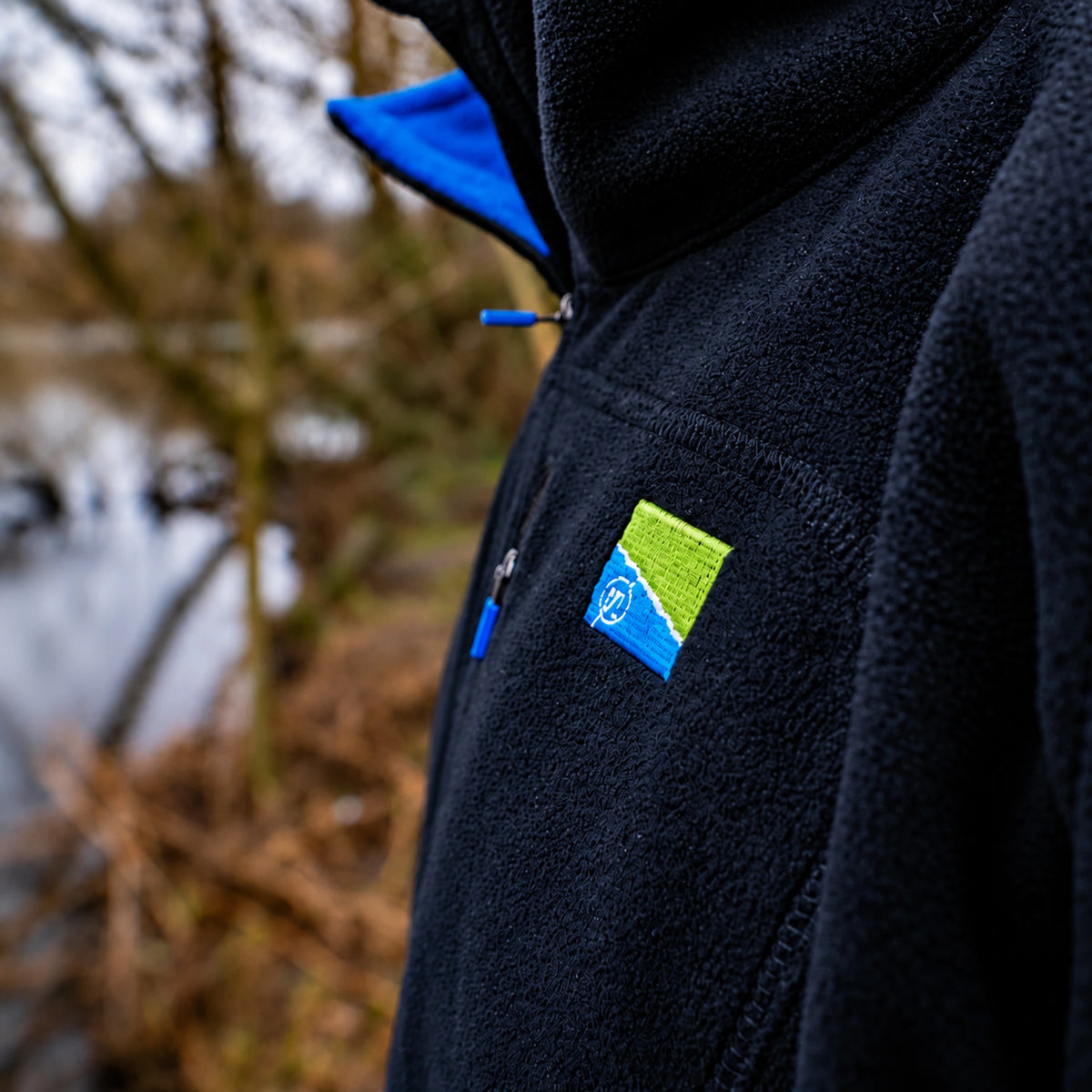 Preston Micro Fleece, schuin detail van blauwe kraagvoering, borstzak en geborduurd Preston-logo