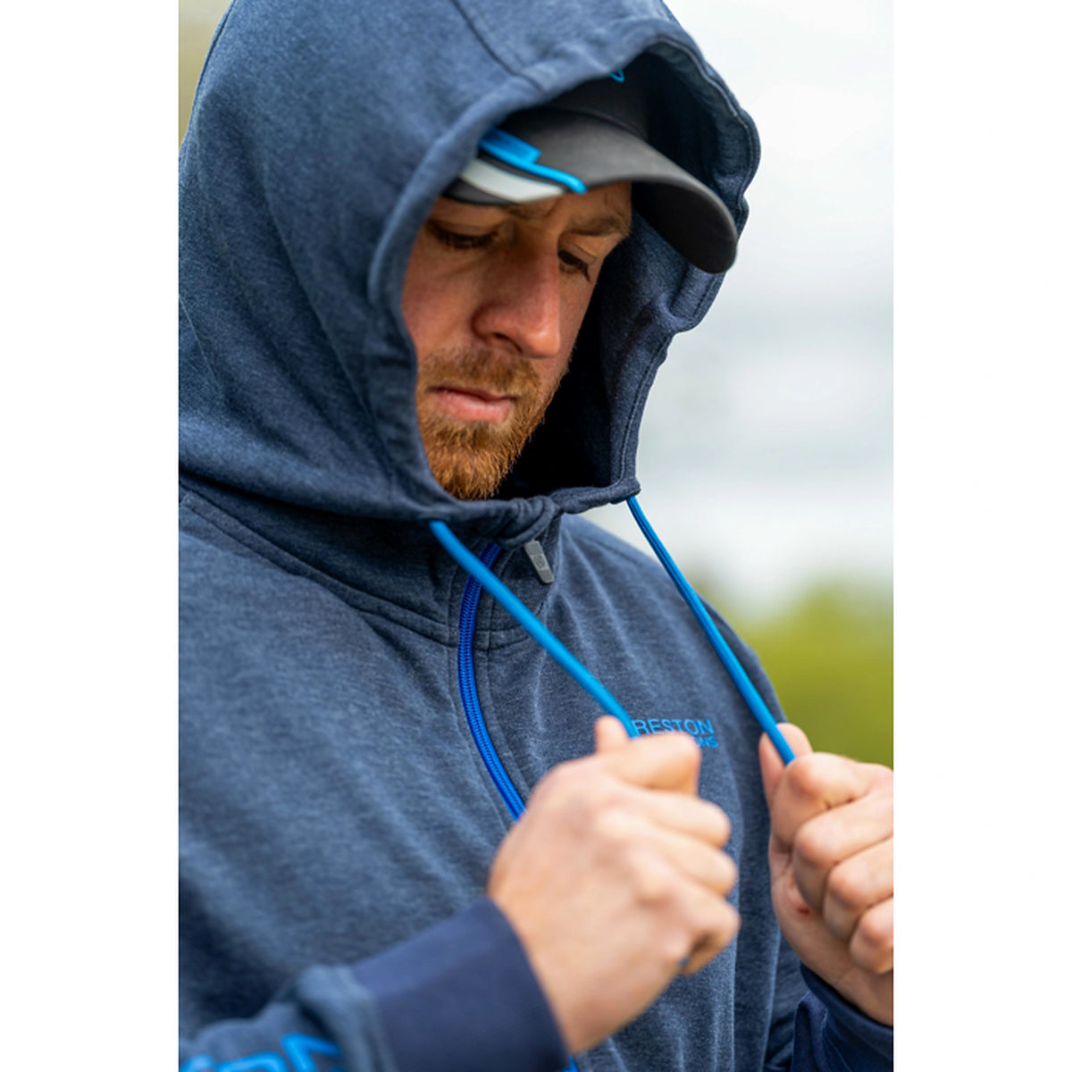 Preston Navy Tide Zip Hoodie – gedragen met opgezette capuchon en blauwe trekkoorden in de handen