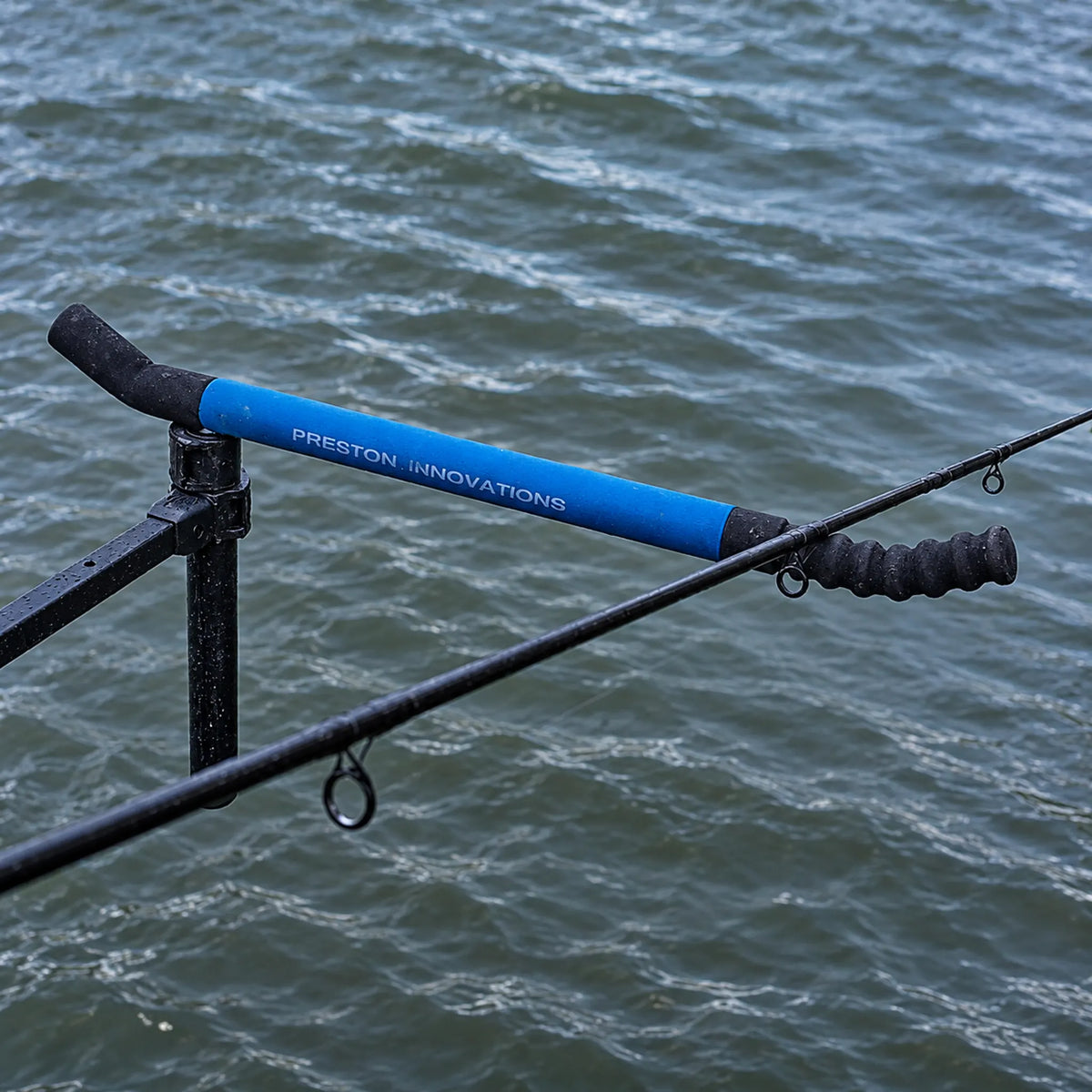 Detail van de Preston Offbox 36 Pro Feeder Arm in gebruik: blauwe feedersteun met hengel boven het water