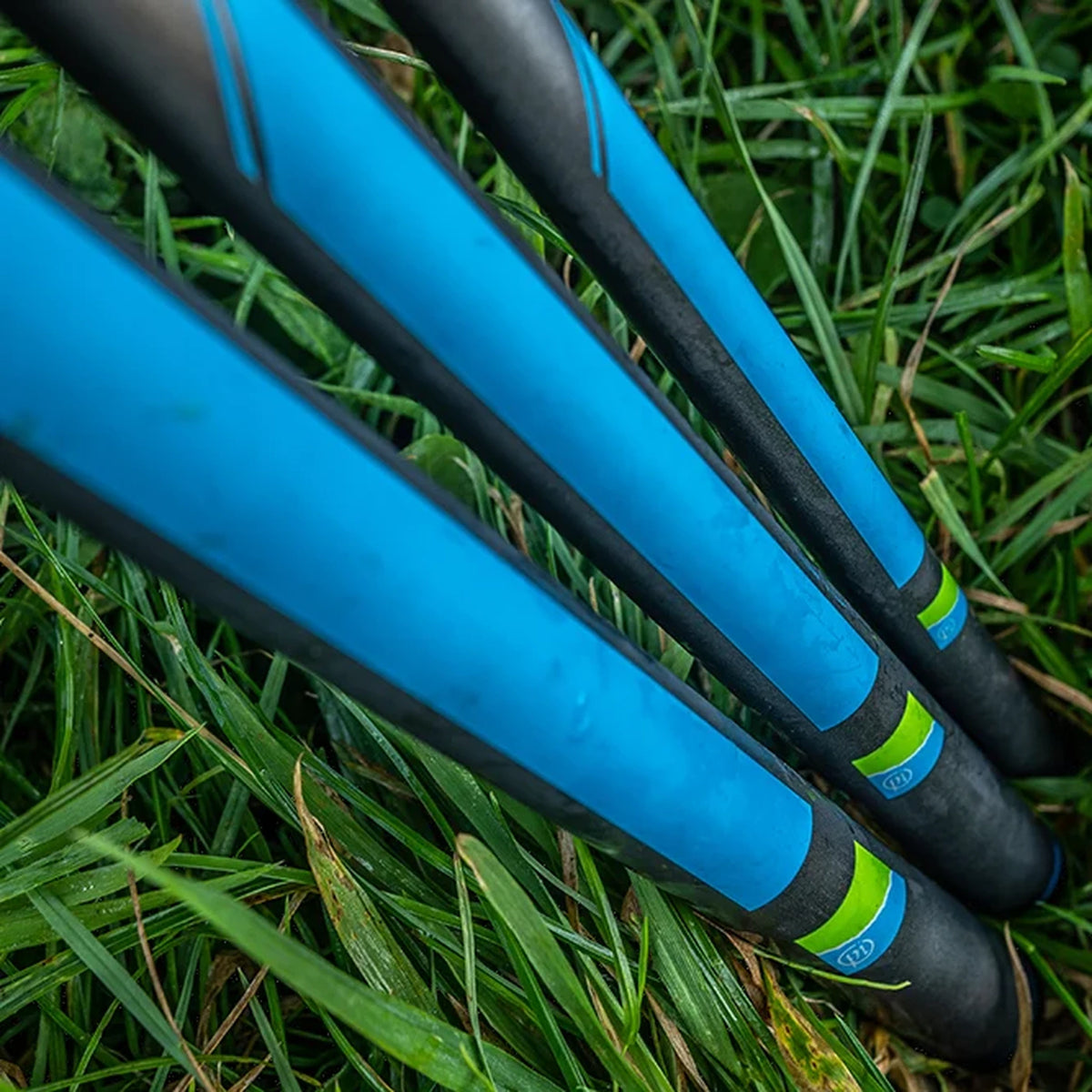 Bovenaanzicht van drie Preston Response Whips in het gras, met blauwe handdeelpanelen, donkere carbon blanks en groen-blauwe labels