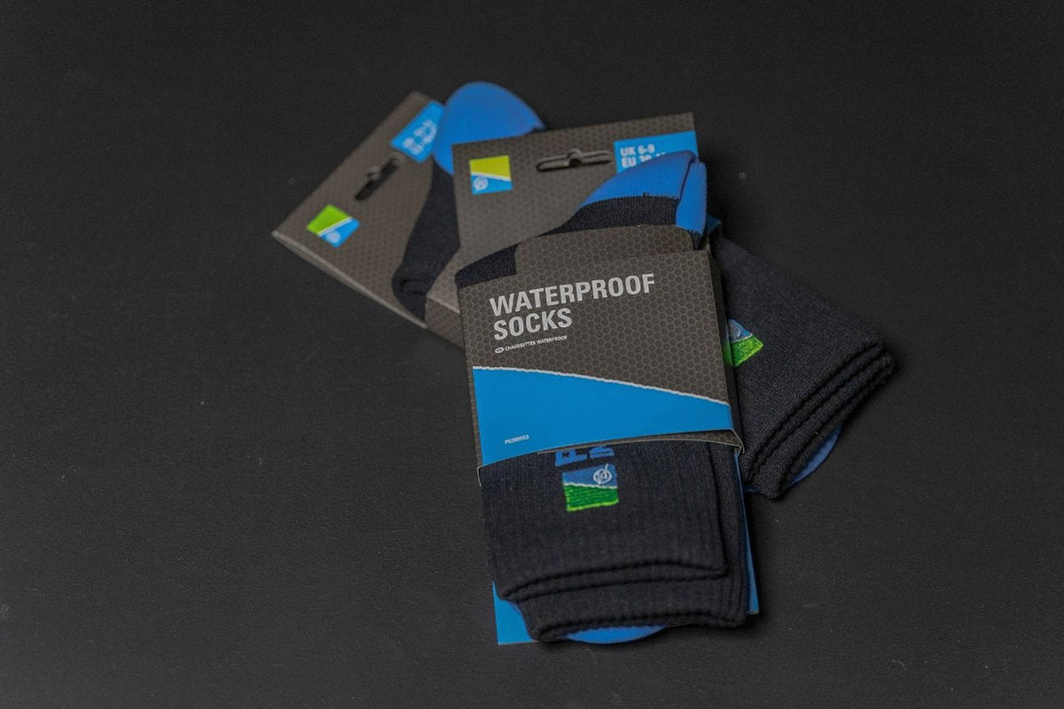 Twee verpakkingen Preston Waterproof Socks op een donkere ondergrond, met de opgevouwen zwart-blauwe sokken