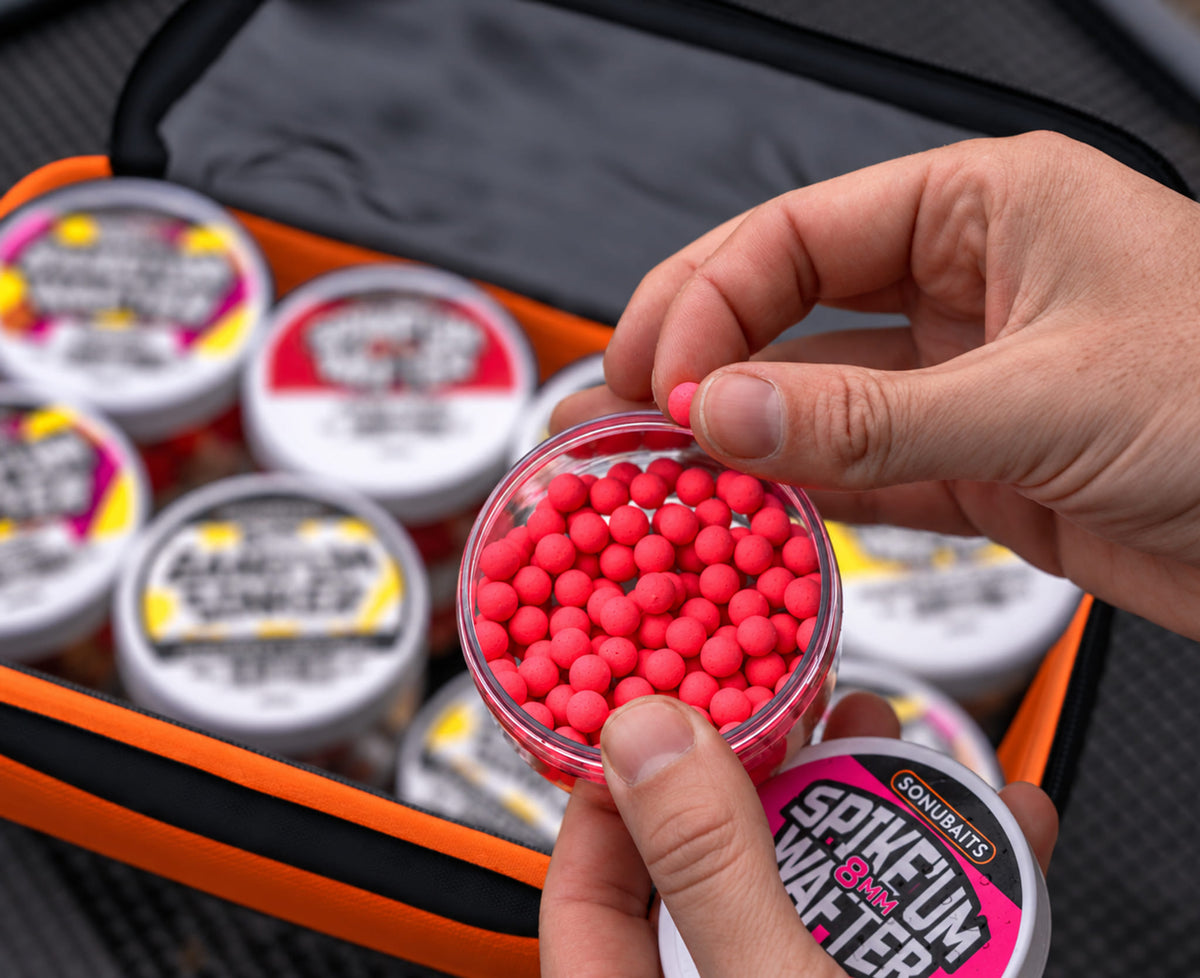 Sonubaits EVA Hookbait Storage Systems: rood haakaas uit een potje boven de open tas selecteren