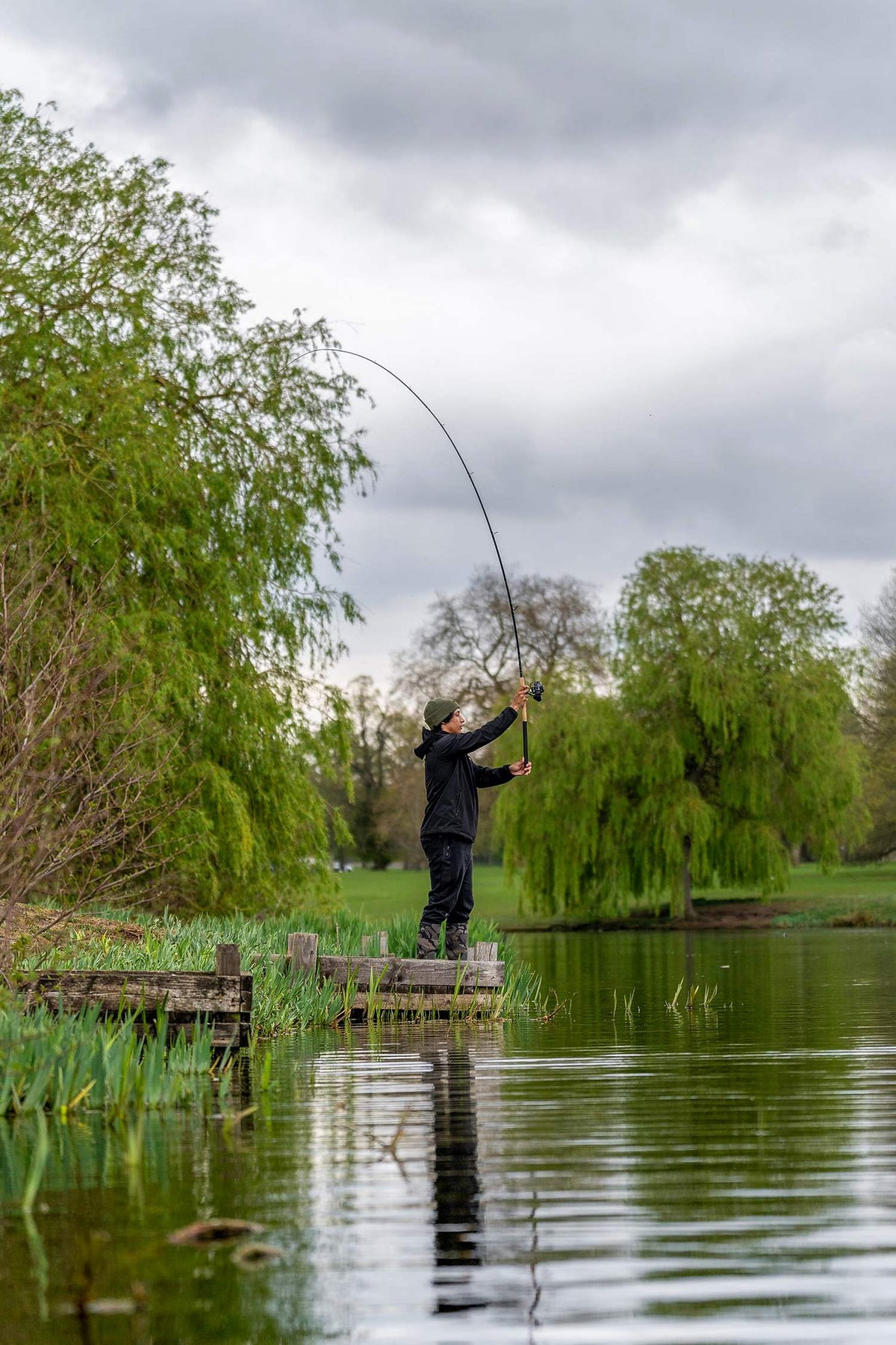 Zebco Feeder Combo – visser werpt vanaf een houten vissteiger met de volledige hengel in beeld